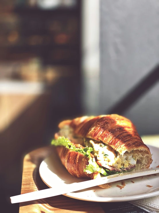 a sandwich sitting on a white plate on a wooden table