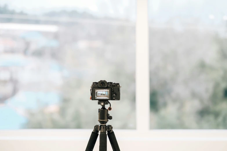 a small tripod with a camera on it next to windows