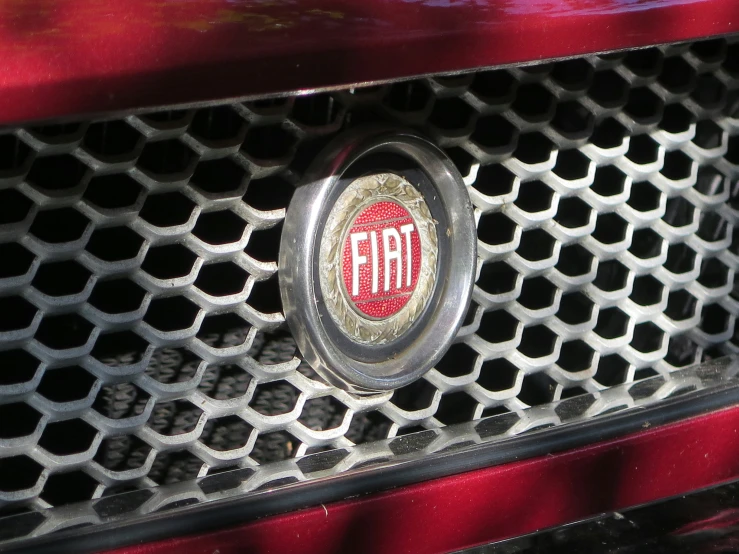 an emblem is pictured on the front grill of a red car