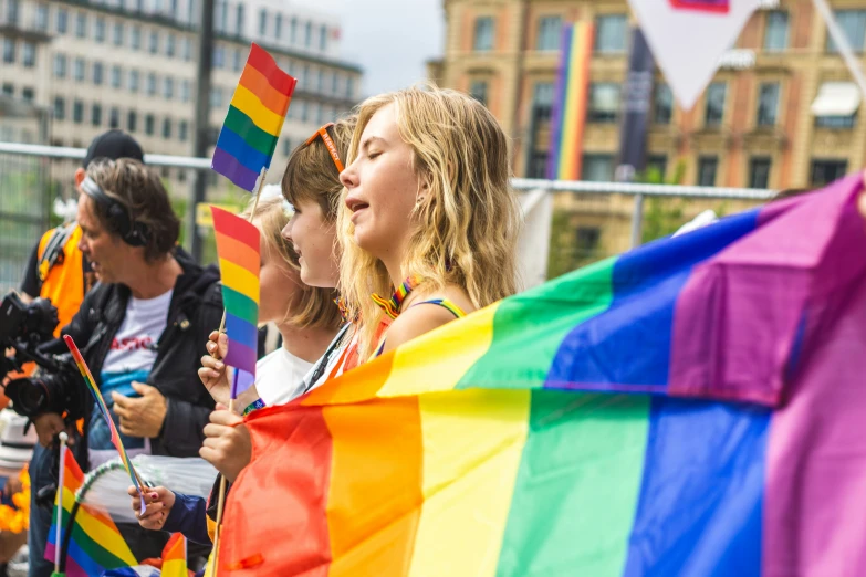 a group of s holding flags and a rainbow colored flag