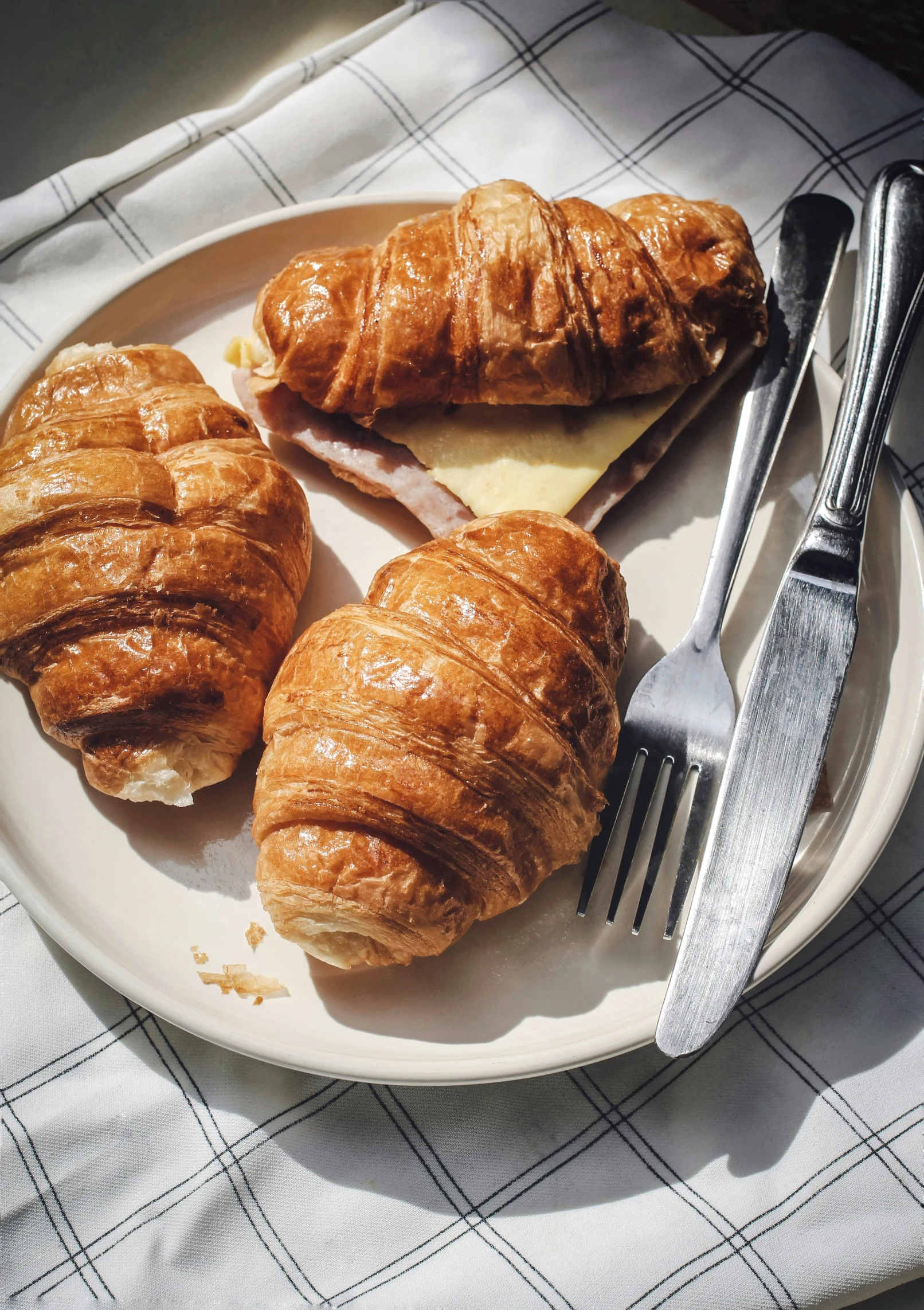 two croissants and a knife sit on a white plate