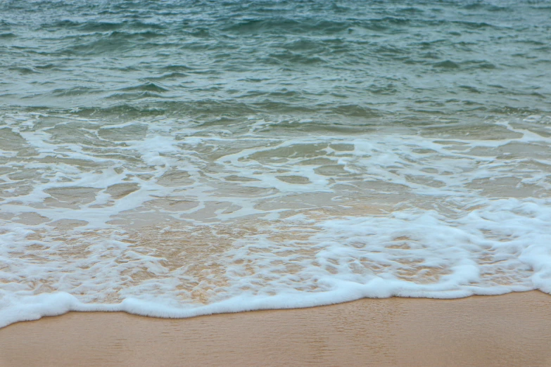 closeup of waves crashing on a sandy beach