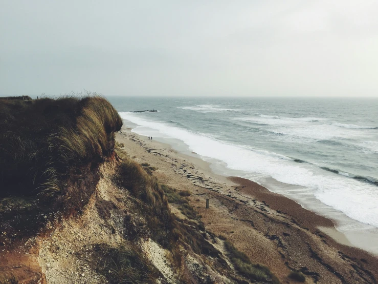 the beach has a cliff and some birds flying in it