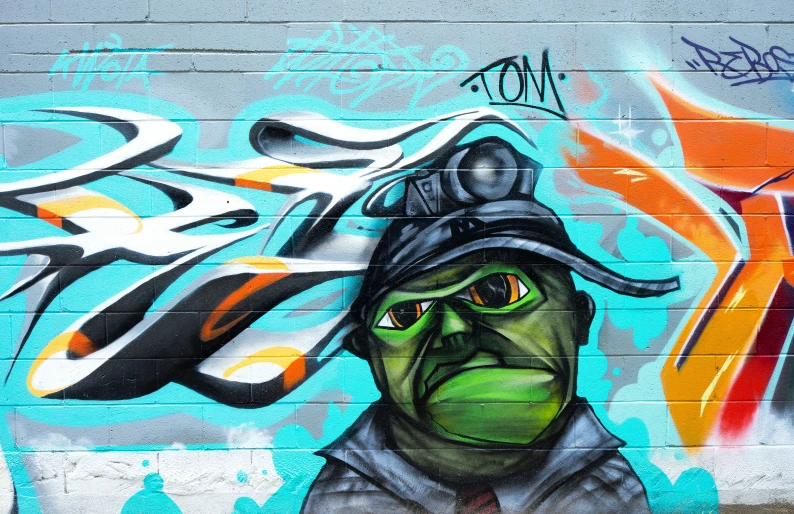 graffiti painted on the side of a building with a man's head wearing a hat