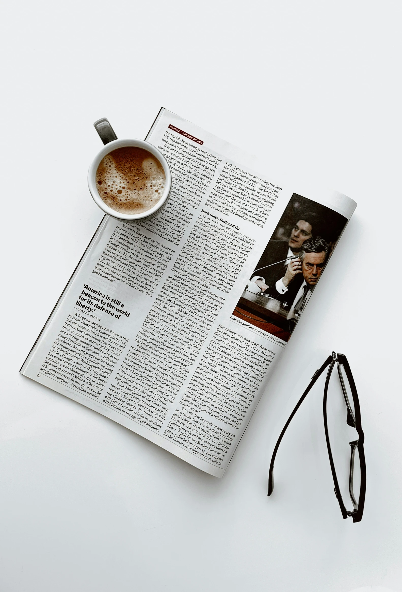 there is a cup of coffee on top of an open magazine