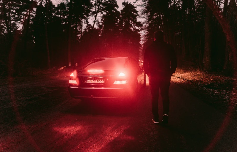 a man standing next to a parked car at dusk