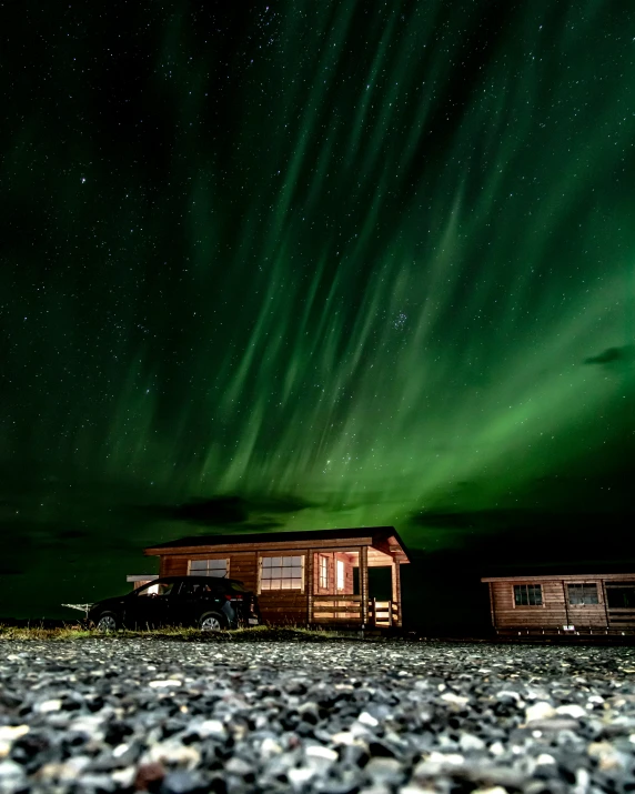 a tiny cabin under the night sky with aurora in the background