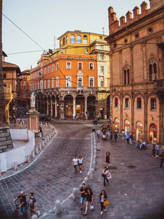 people walking down a cobblestone street lined with buildings