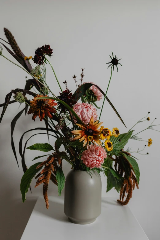 a vase filled with assorted flower blooms on top of a white counter