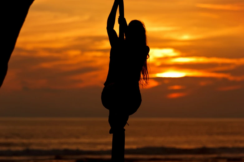 silhouette of woman standing by water at sunset