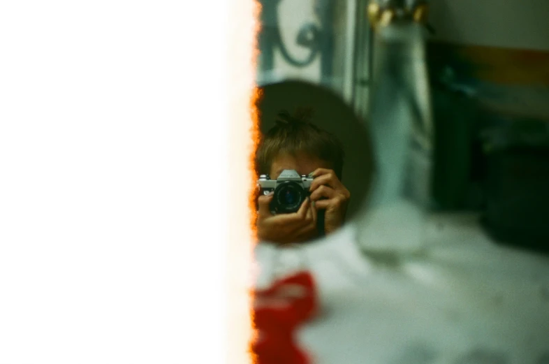 a person is holding a camera while standing in front of the mirror