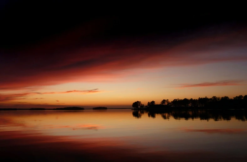 the sun is setting over the calm water