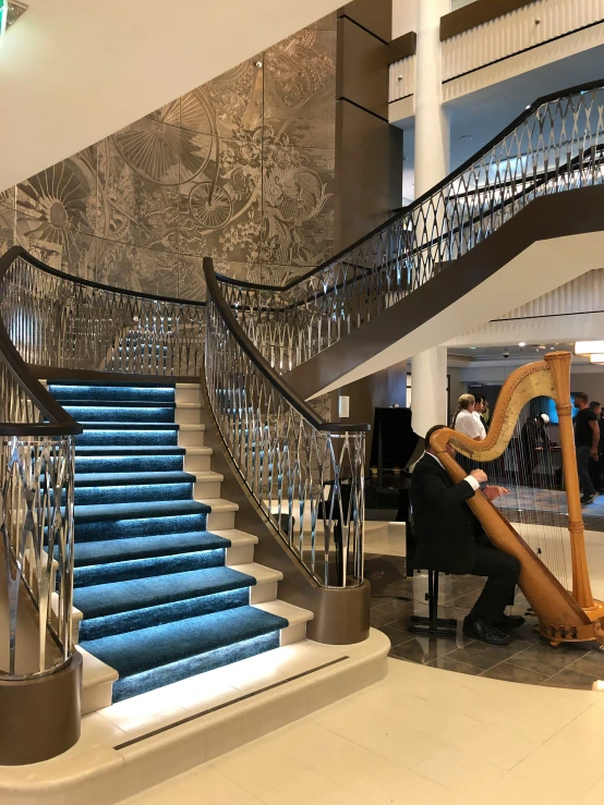 a woman is playing an elaborate harp in front of some stairs