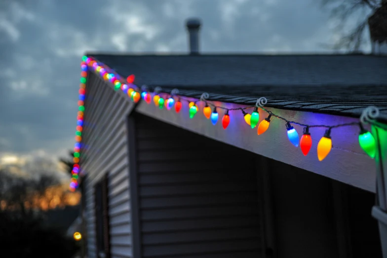 outdoor christmas lights on roof of home under cloudy skies