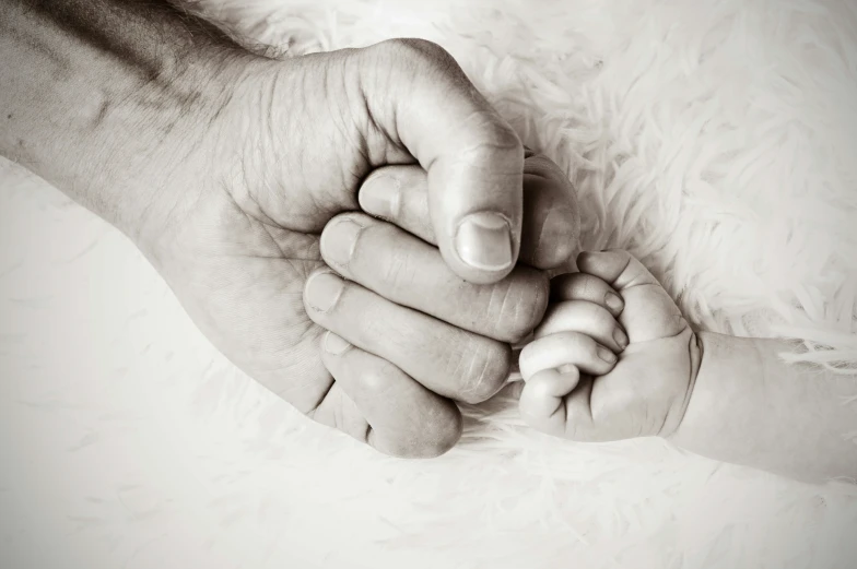 two hands hold the bottom of a baby's foot