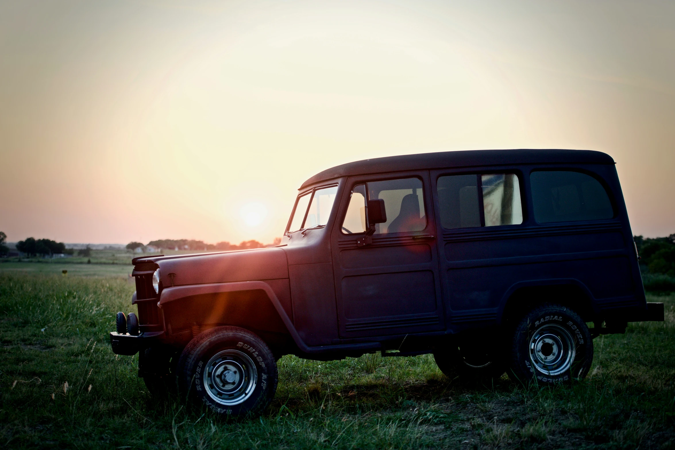 a jeep in the middle of a large field of grass