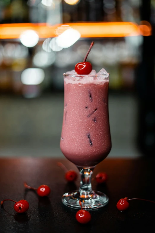 pink iced beverage garnished with a cherries