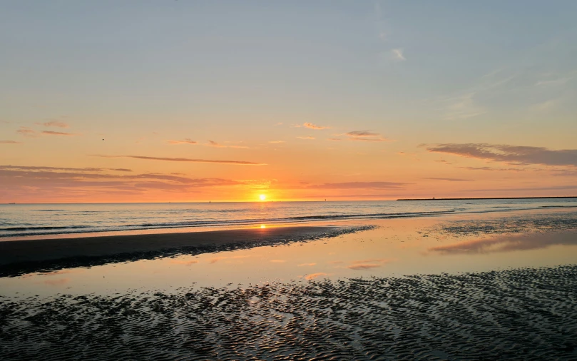 the setting sun reflecting in the beach water