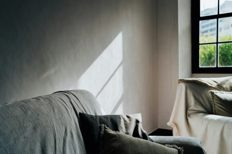 a grey couch sitting next to a window with a blanket on it