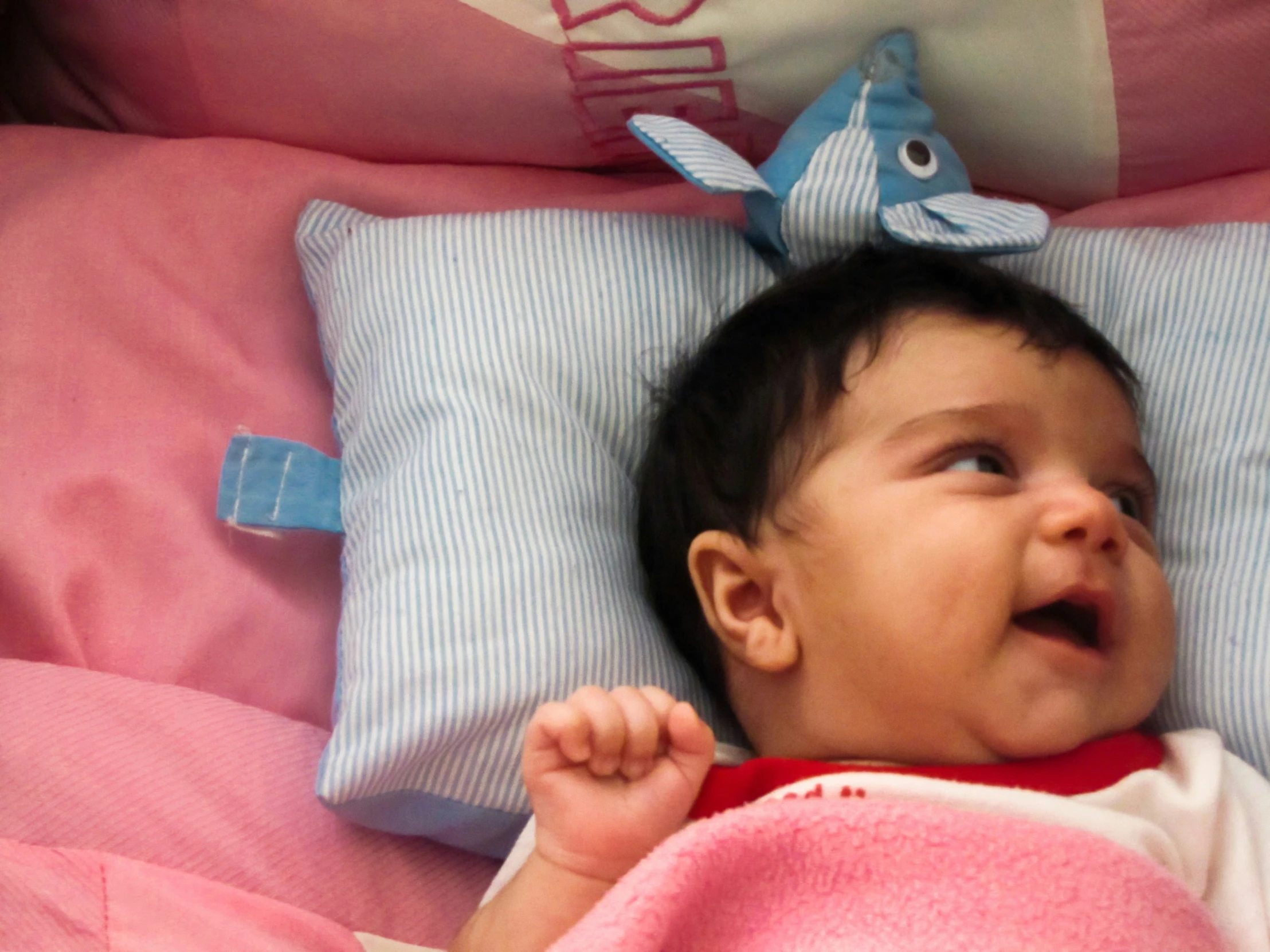 baby on pink bed wearing an angel dress and smiling