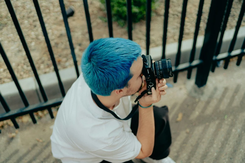 the man in white shirt is using the camera to take a picture