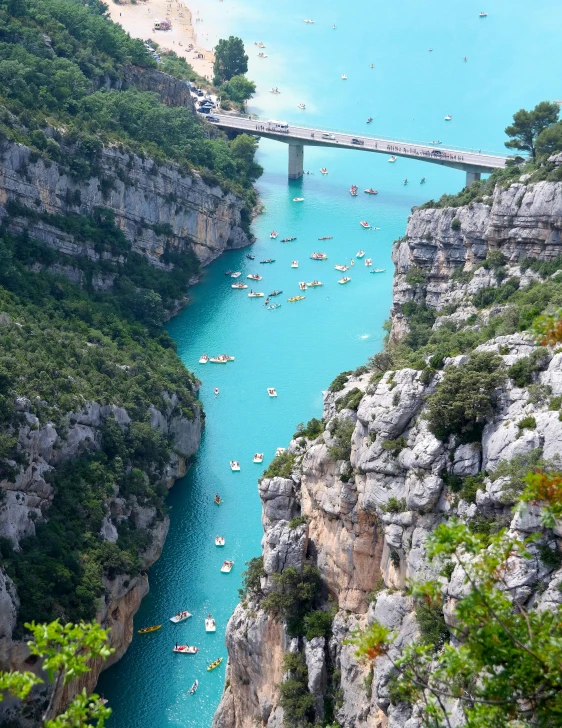 an aerial view shows people rafting, sailing and standing on the riverbank