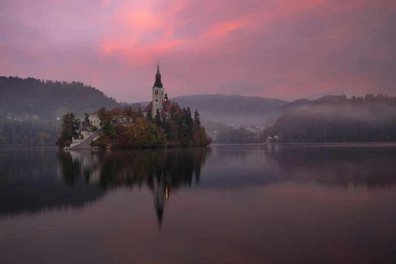 a big lake with some trees on it and a church at the top