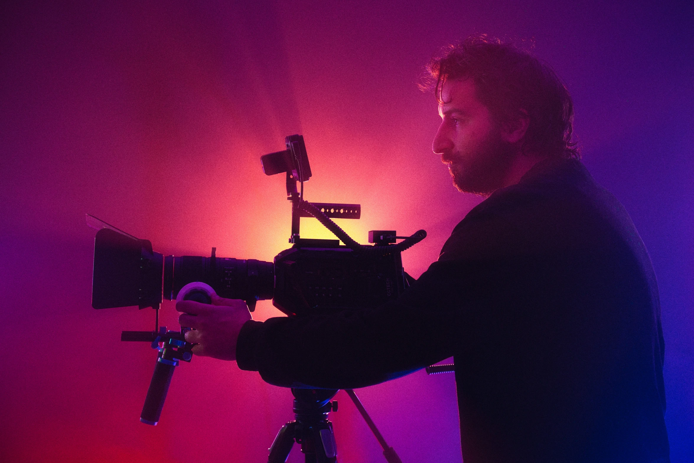 the cameraman in front of the dark wall and a bright light