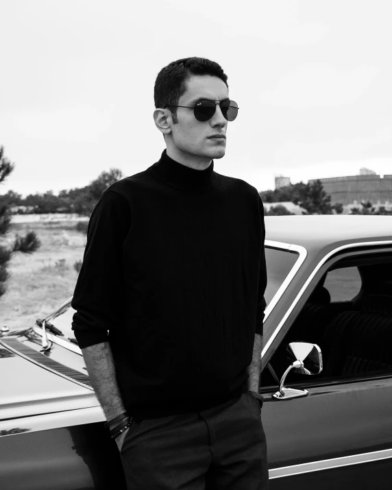 a man is posing by a car with sun glasses