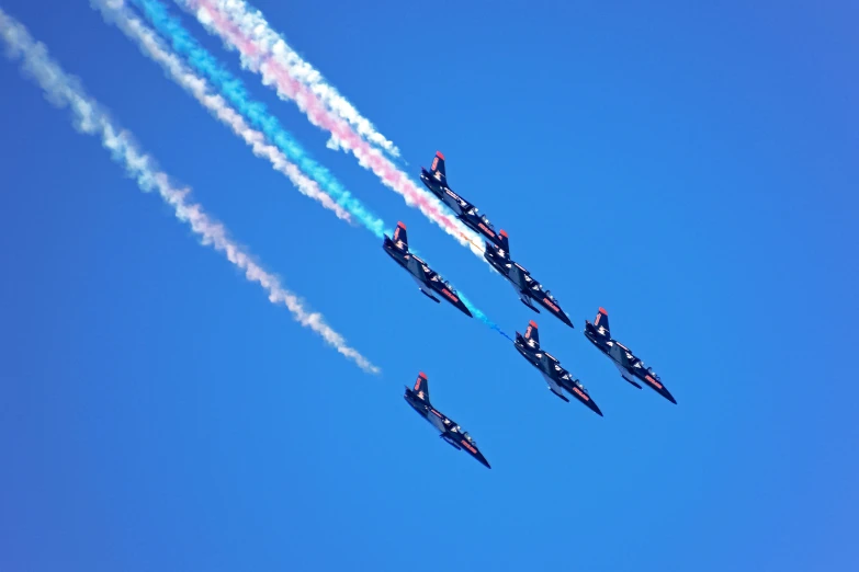 four planes leaving colorful trails in the sky