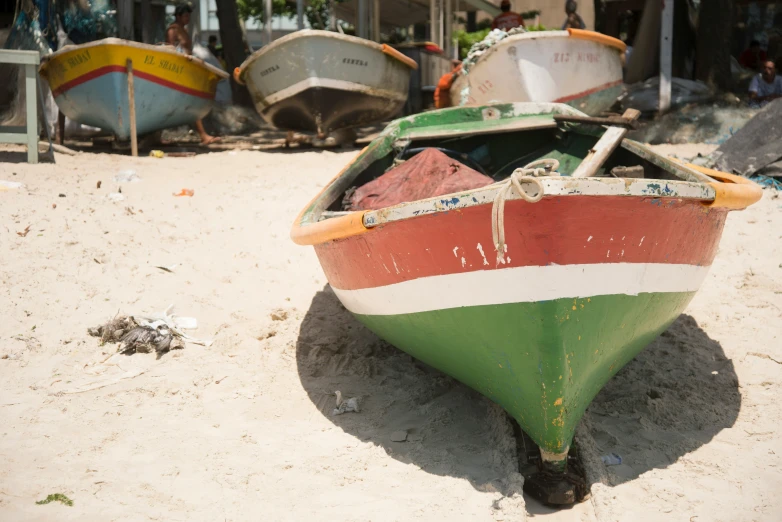 a boat sitting on the beach with other boats parked nearby