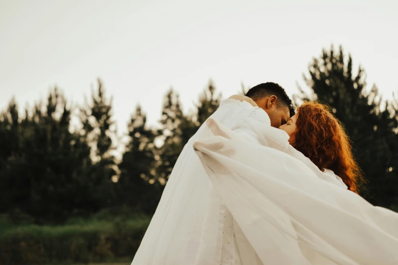 a man and a woman wrapped in veils kiss