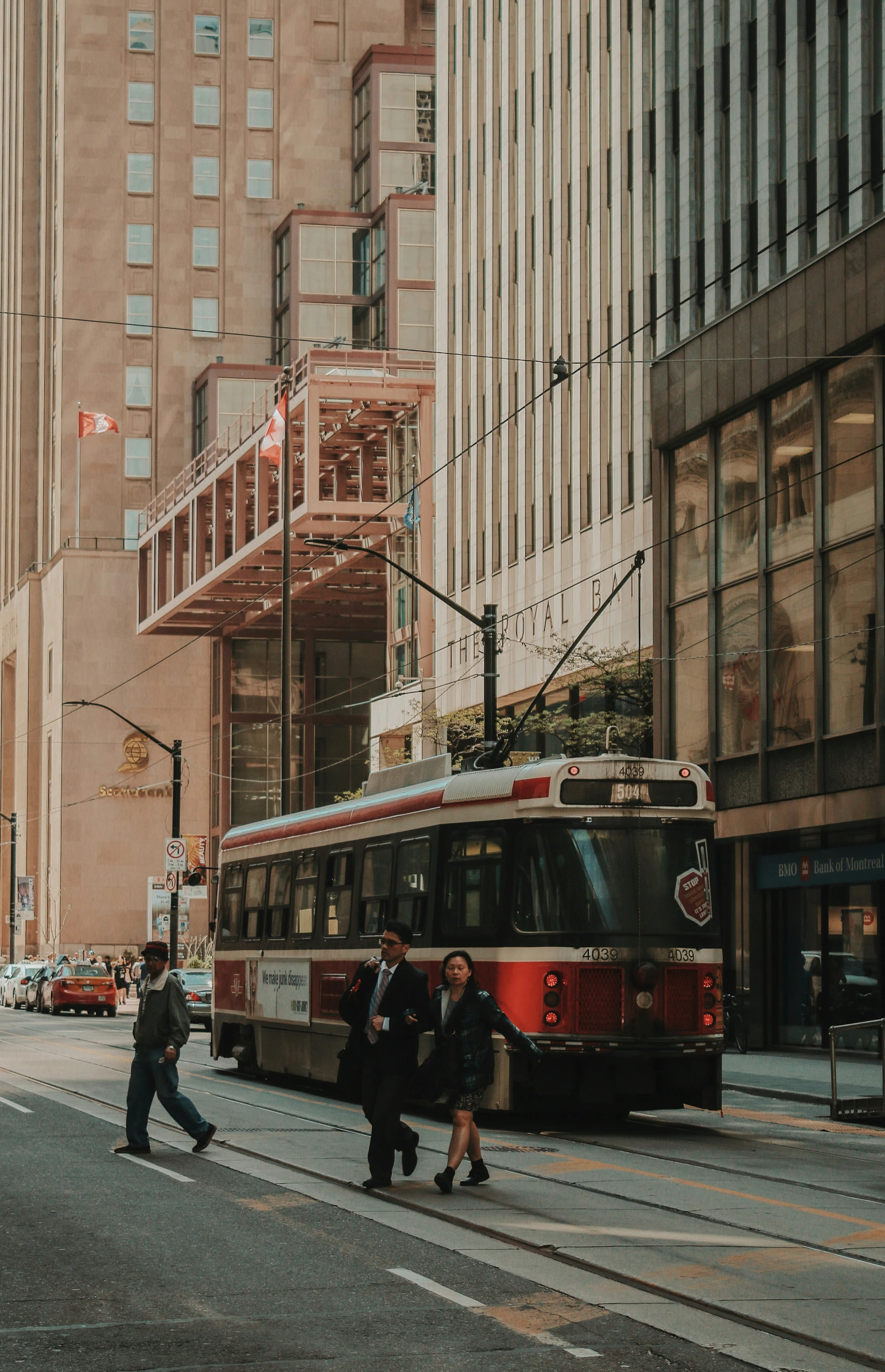 pedestrians are crossing the street in front of a red trolley