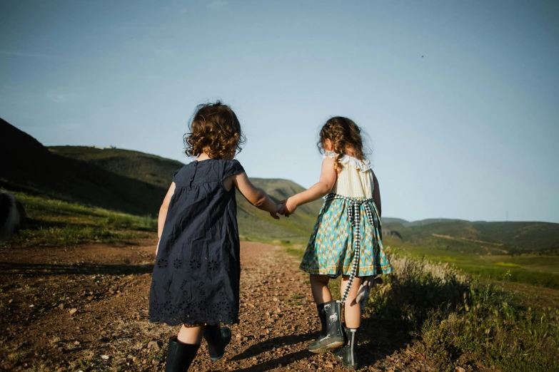 two little girls walking down a dirt road