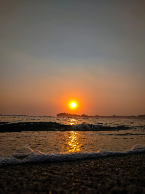 the sun is setting over the ocean with waves