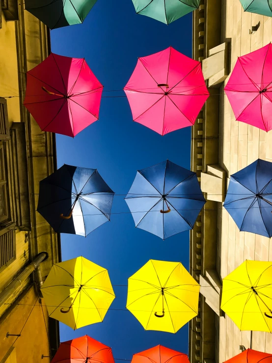 several colorful umbrellas flying from a building to the sky