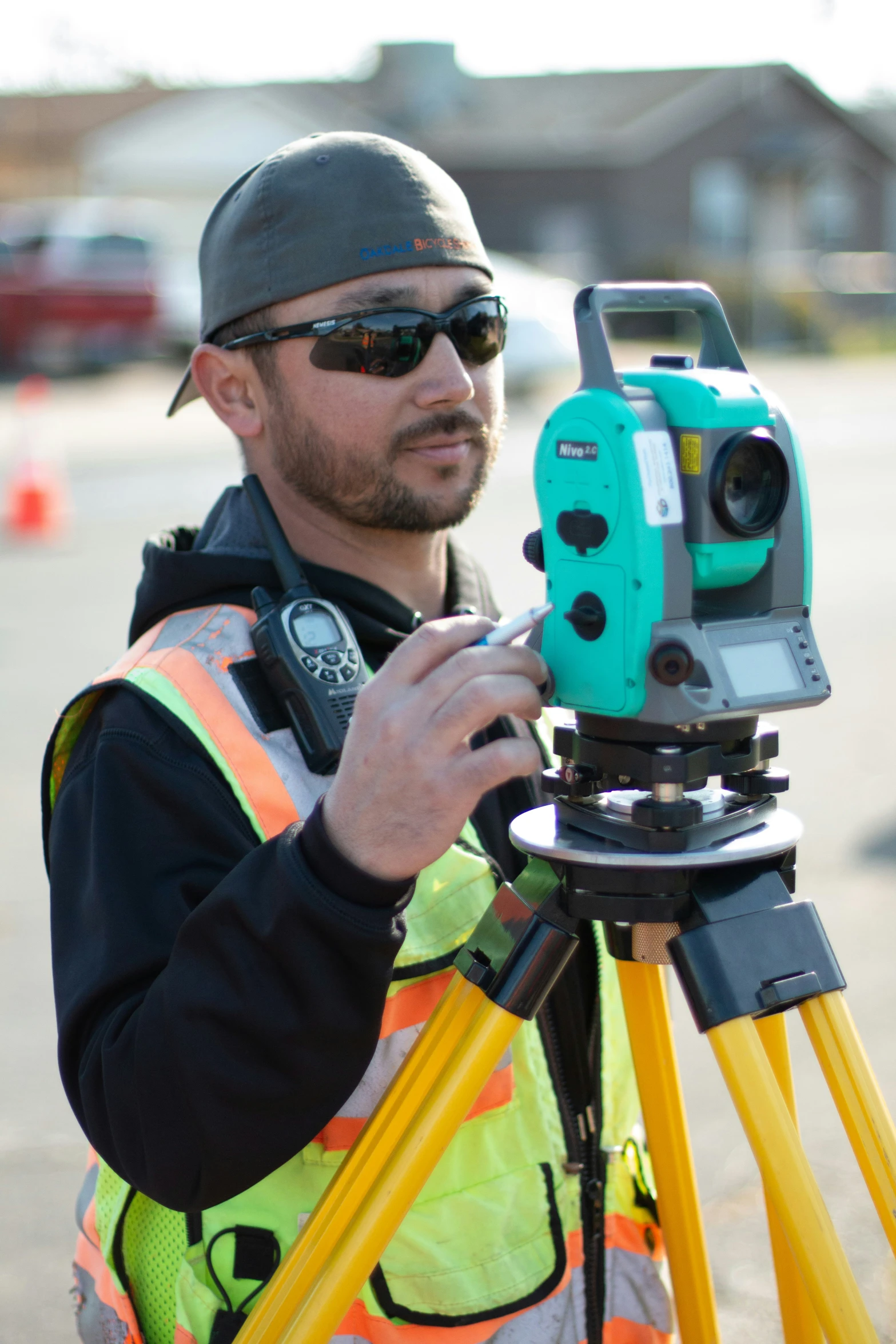 a man in safety vest holding a camera on a tripod