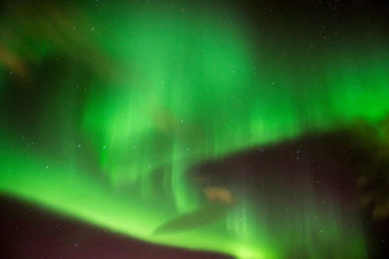 a large bright green aurora bore over the night sky