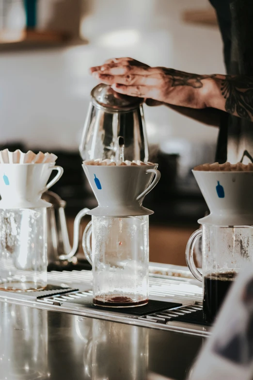 two people standing by a coffeemaker pouring milk from a blender