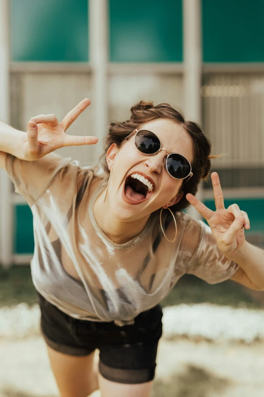 a girl wearing sunglasses making the number two gesture