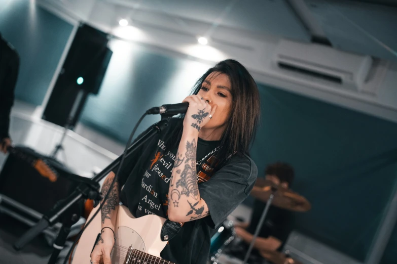 a woman with tattoos plays a guitar on stage