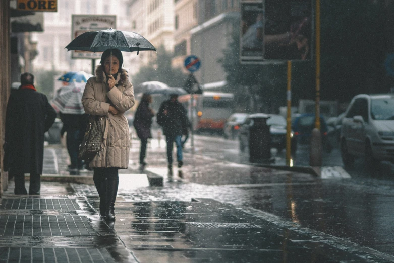 a woman on a sidewalk with an umbrella in the rain