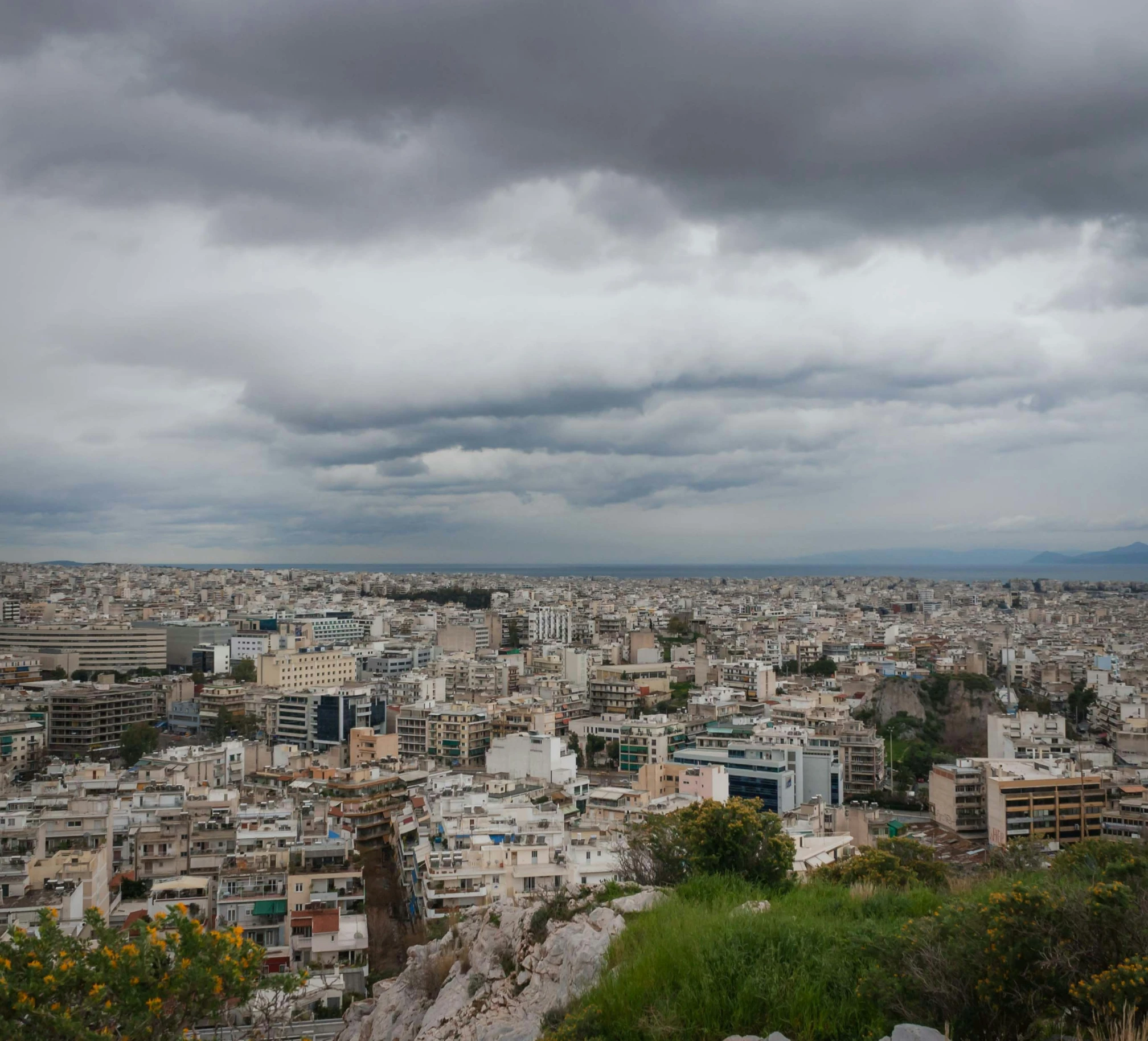 a city with gray clouds above some trees