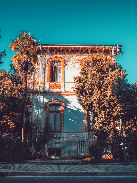 a very tall house with many windows surrounded by trees