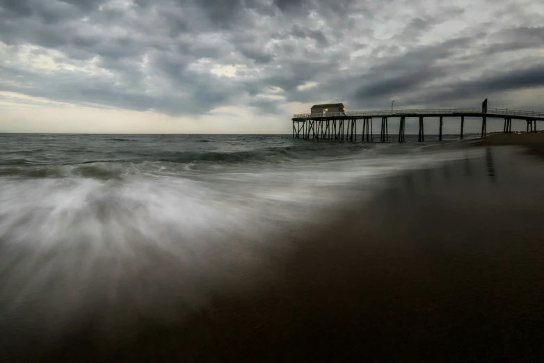 a pier in the water and waves crashing in front of it