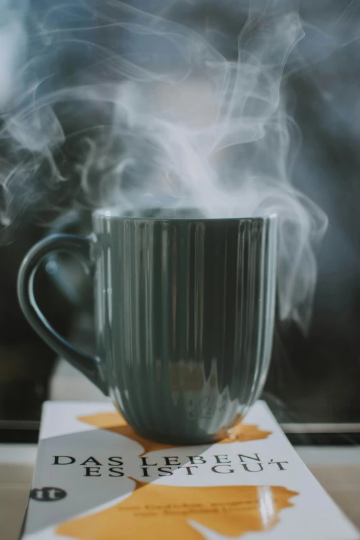 steaming coffee cup on card with book next to it