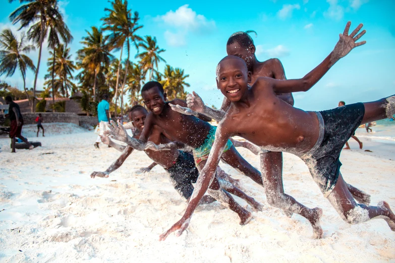 the boy in the black and blue swim trunks dives into white sand