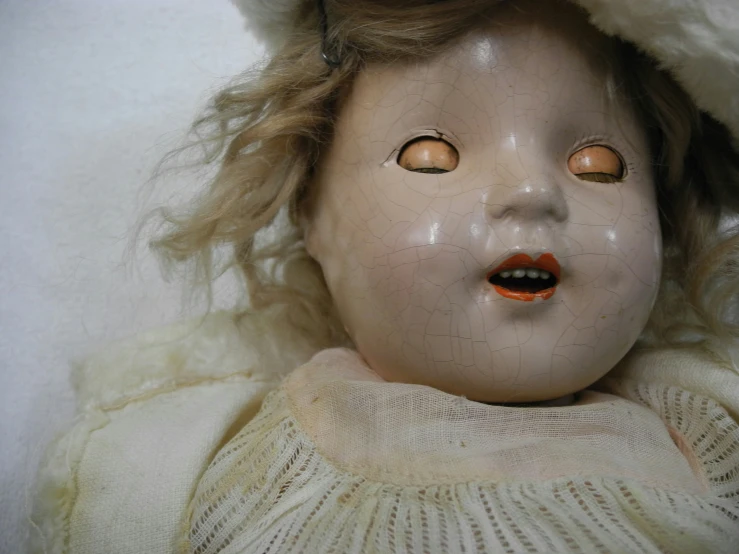 a close up of an old doll wearing a fur jacket