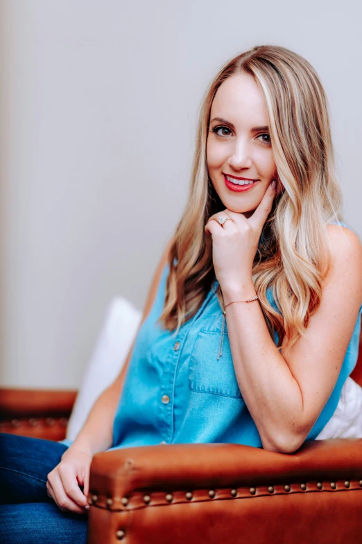 a blonde woman in a blue top is sitting on a chair