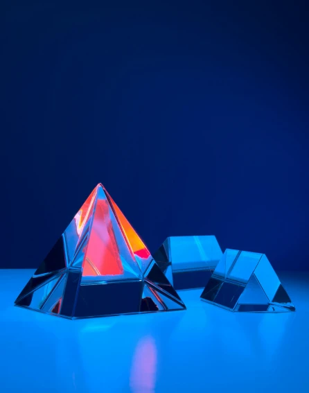 three crystal pyramids of different colors on a table